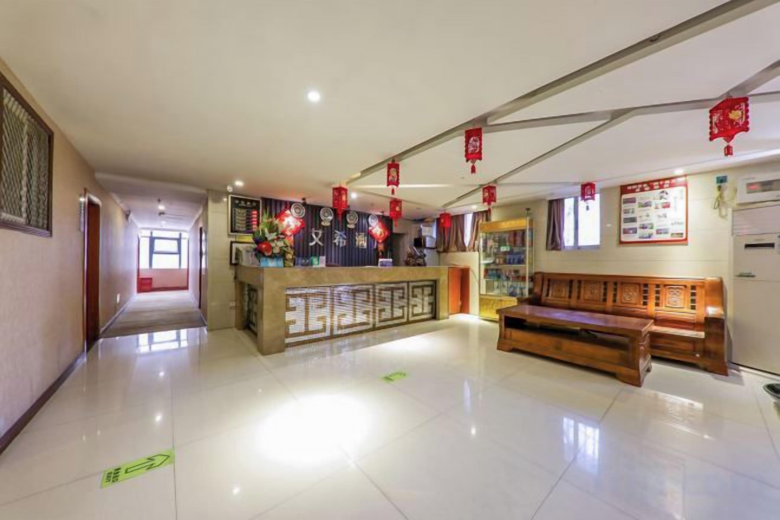 Un vestíbulo de hotel con recepción, zona de estar y un pasillo que da a otras habitaciones.
