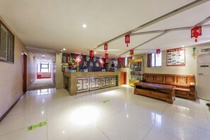 A hotel lobby with a reception desk, seating area, and a corridor leading to other rooms. - AiXi Traving with hostel (Chongqing)