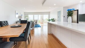 Une cuisine moderne avec des meubles blancs, un grand îlot central et un four encastré.