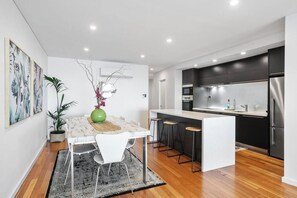 Une cuisine moderne avec un îlot central blanc, des meubles noirs et des appareils électroménagers en acier inoxydable.