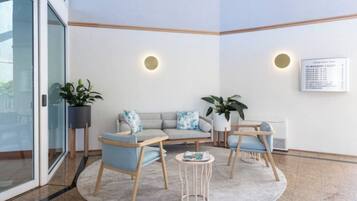 A modern waiting area with a sofa set, chairs, a small table, and potted plants.