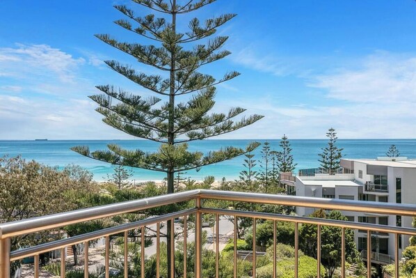 A balcony with a railing overlooking a beach and ocean.