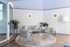 A modern waiting area with a sofa set, chairs, a small table, and potted plants.