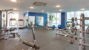 A gym with various exercise equipment, large windows, and a blue accent wall. - Apartment M503 - panoramic ocean views for miles! (Scarborough)