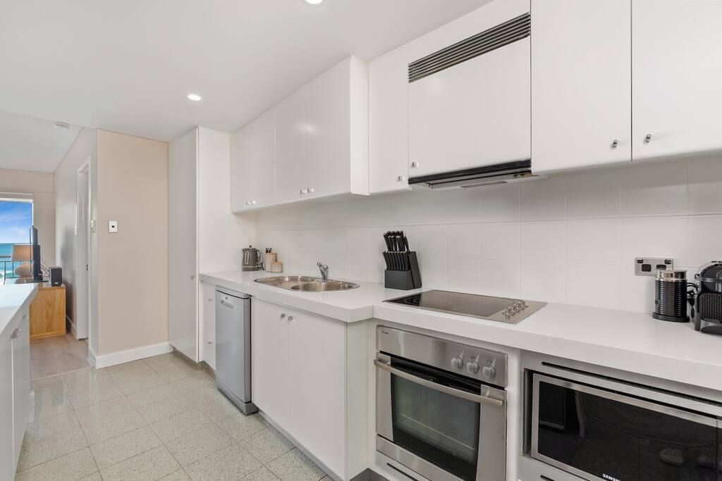 A modern kitchen with white cabinetry, stainless steel appliances, and a dishwasher.