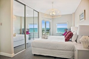 A bedroom with a large bed, a glass door leading to a balcony, and a view of the sea. - Apartment M503 - panoramic ocean views for miles! (Scarborough)