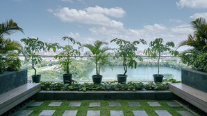 A rooftop garden with potted plants and a view of a lake and cityscape.