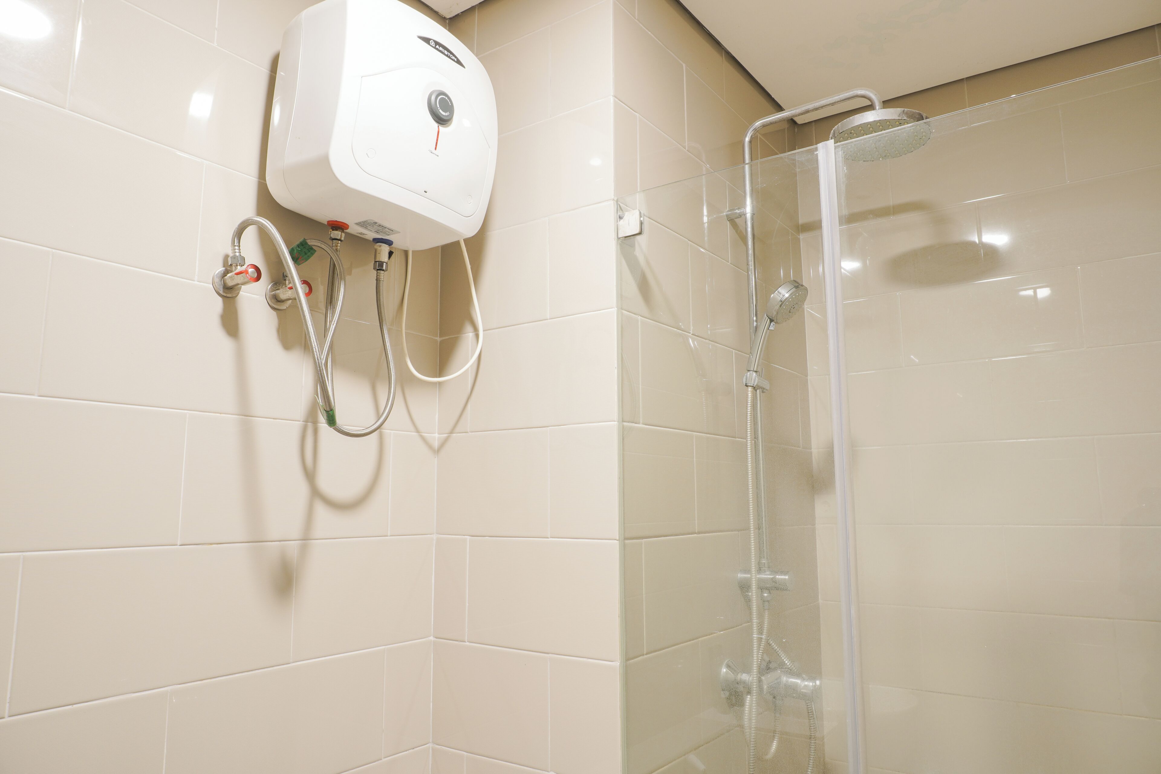 A shower area with a glass enclosure, a wall-mounted hand dryer, and a control panel.