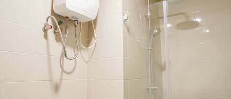 A shower area with a glass enclosure, a wall-mounted hand dryer, and a control panel.