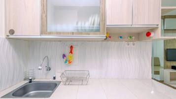 A modern kitchen with a stainless steel sink, wooden cabinets, a white tiled backsplash, and a small wire basket.