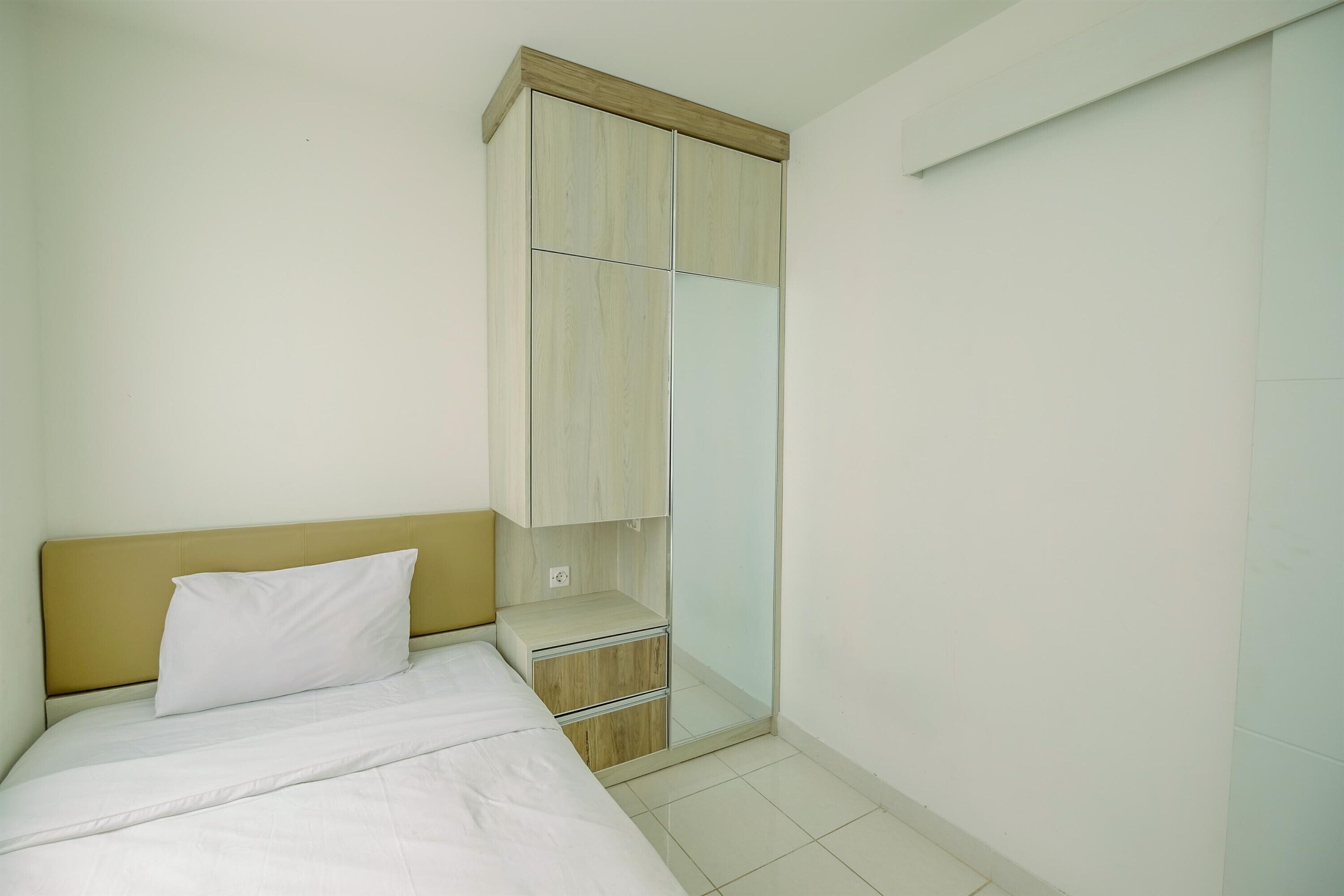 A bedroom with a bed, a wooden headboard, a wardrobe with a mirror, and a small bedside table.
