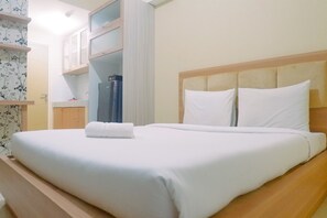 A neatly made bed with white linens, a wooden headboard, and a small bedside table with a lamp.