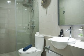 A modern bathroom with a glass shower enclosure, a toilet, and a sink with a mirror above it.