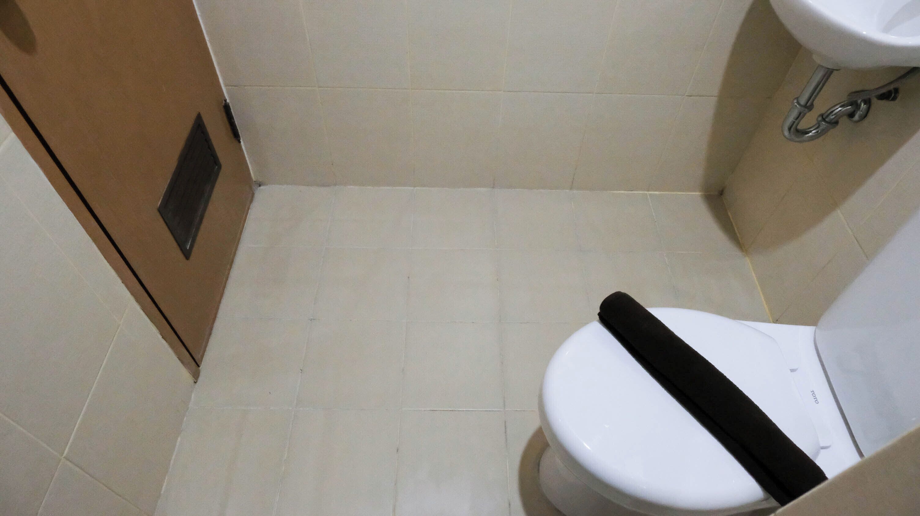 A small, clean bathroom with a white toilet, a sink, and tiled walls.