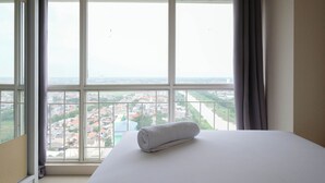 A hotel room with a large window offering a city view.