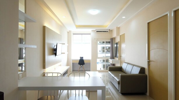 A modern living room with a dining area, a sofa, a TV mounted on the wall, and a window with curtains.