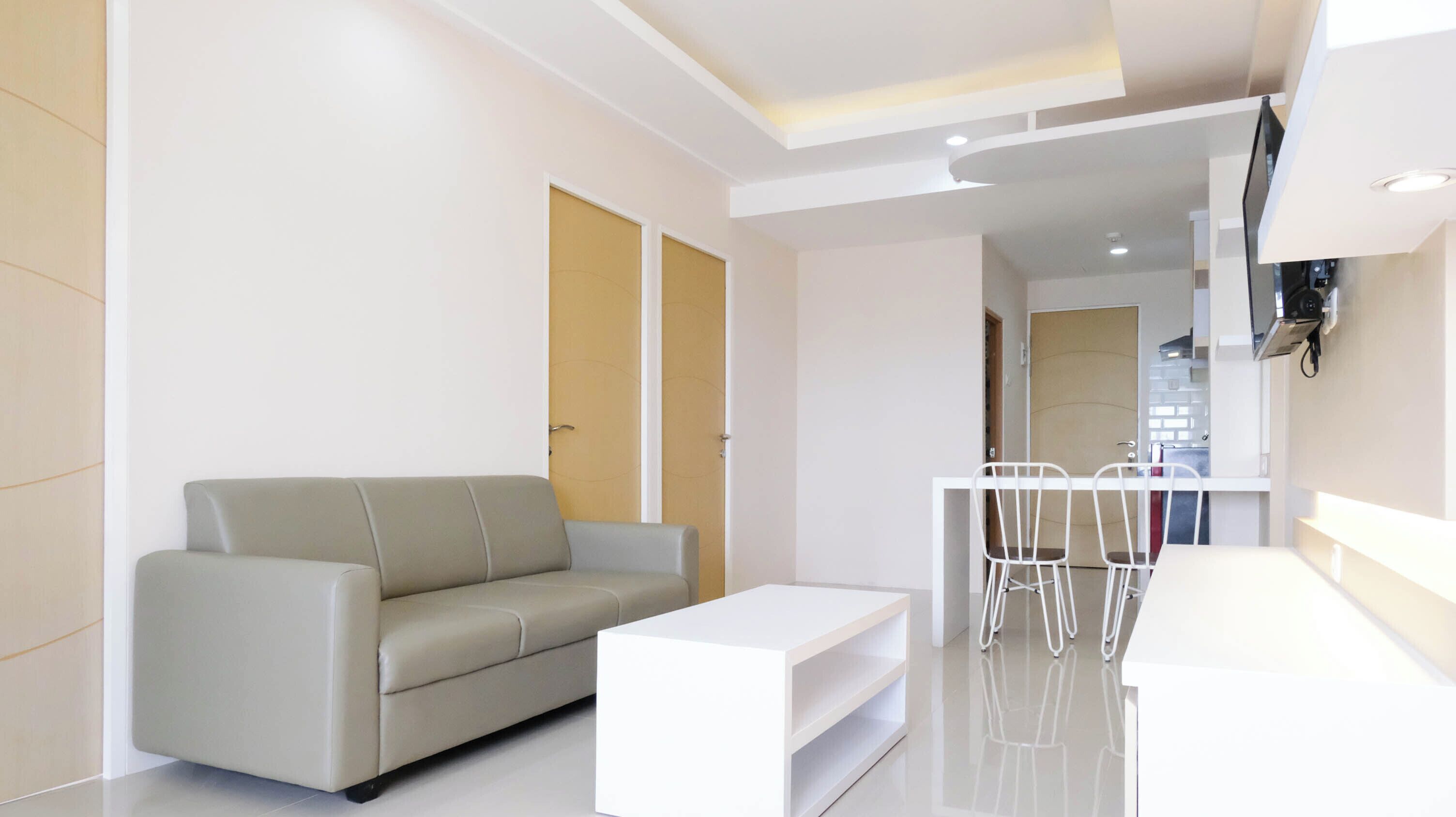 Un salon moderne avec un canapé gris, une table basse blanche et un coin repas comprenant une table et des chaises blanches.