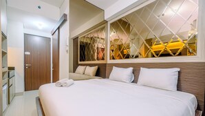 A hotel room with a large bed, a wardrobe, a mirror, and a window with a geometric pattern.