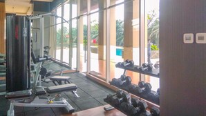 A gym with exercise equipment, large windows, and a view of the outdoors.