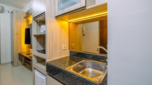 A compact kitchen with a built-in microwave, a sink, and a countertop with a black granite finish.