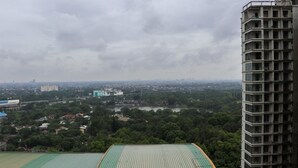 A high-rise building with a green roof, overlooking a cityscape with various buildings and a river.