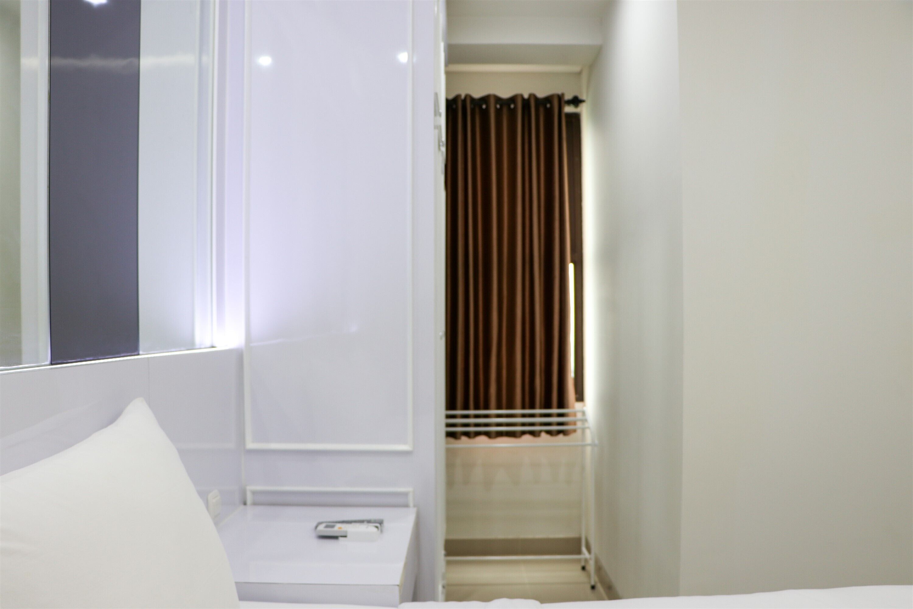 Une chambre d’hôtel avec un lit, une table de chevet, un miroir et une fenêtre avec des rideaux.