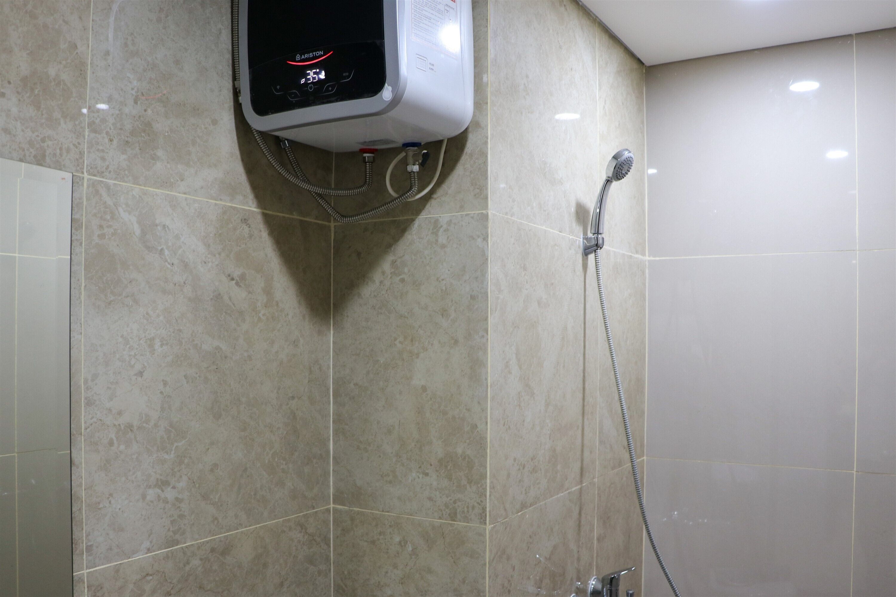 Une salle de bain moderne dotée d’un panneau de commande numérique pour la douche, d’un pommeau de douche à main et de murs recouverts de carreaux.