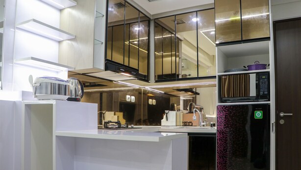 A modern kitchen with white cabinetry, a built-in microwave, and a refrigerator.
