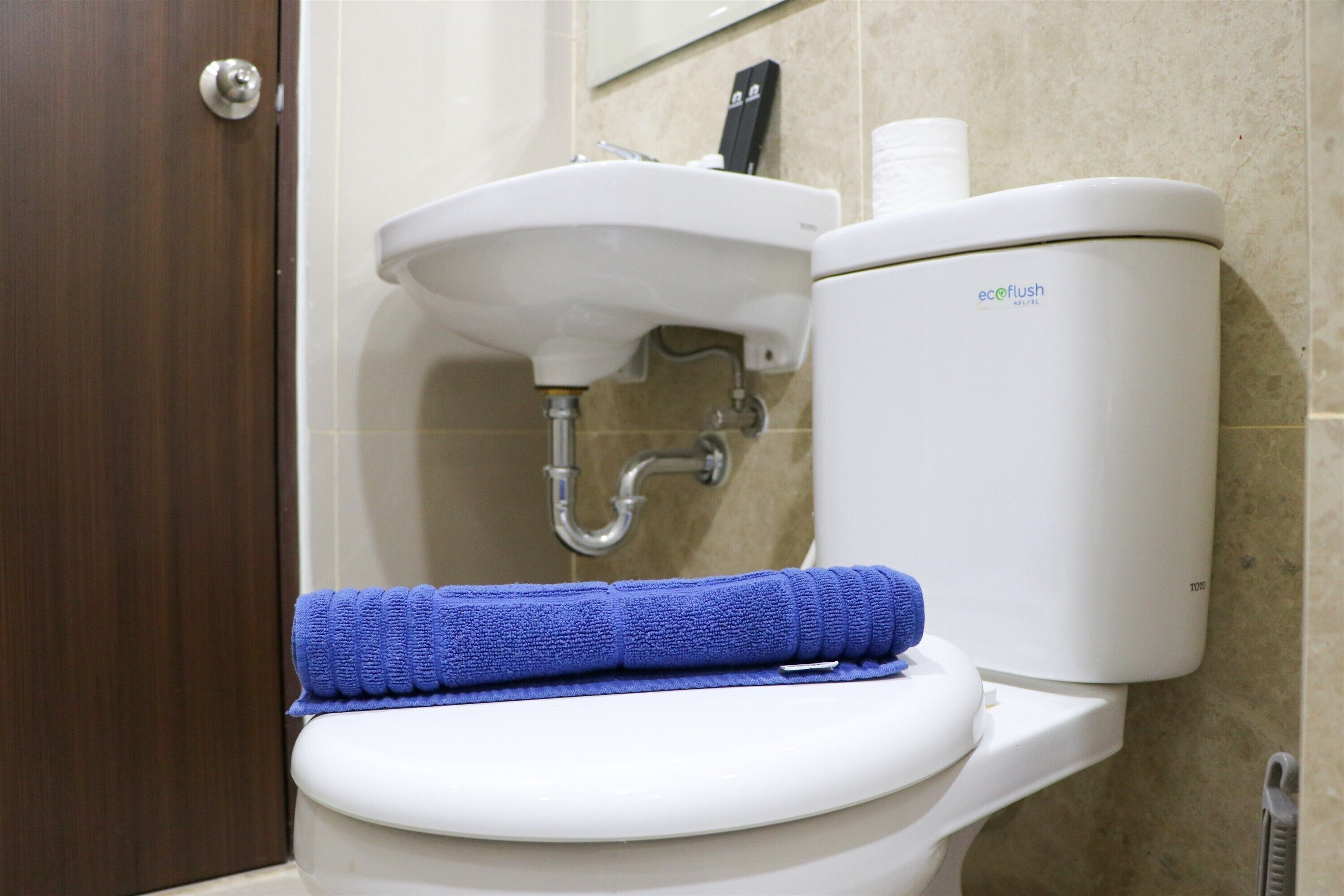 Sanitário com uma toalha azul no assento, uma pia branca e um suporte para papel higiênico.