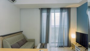 Una sala de estar moderna con un sofá, una mesa de centro, un televisor y un balcón con cortinas.