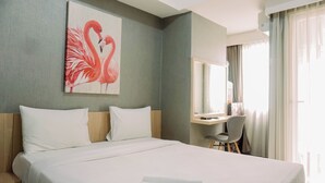 Habitación de hotel con una cama grande, un escritorio con silla, un espejo y un cuadro de flamencos en la pared.