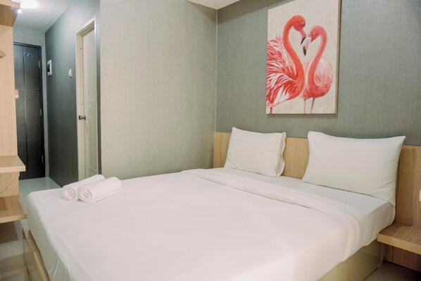 Ein Hotelzimmer mit einem Bett, einem Flamingo-Gemälde und einer Tür.
