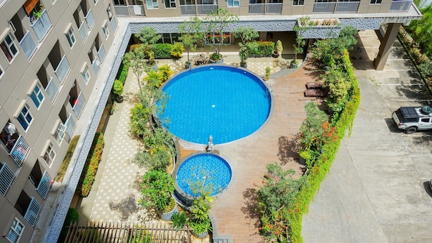 An aerial view of a hotel courtyard with a central swimming pool, surrounded by greenery and a covered seating area. - Comfort 2Br At 3Rd Floor Baileys Apartment (South Tangerang)