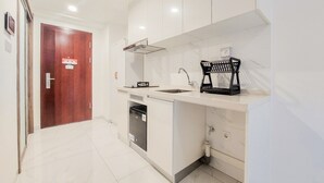 A compact kitchen with a dishwasher, a sink, and a black coffee machine on the countertop. - Homey And Simply Look Studio Sky House Alam Sutera Apartment (Tangerang)