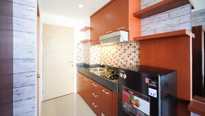 Une cuisine moderne avec des meubles en bois, un réfrigérateur noir et un pare-feu en carreaux.