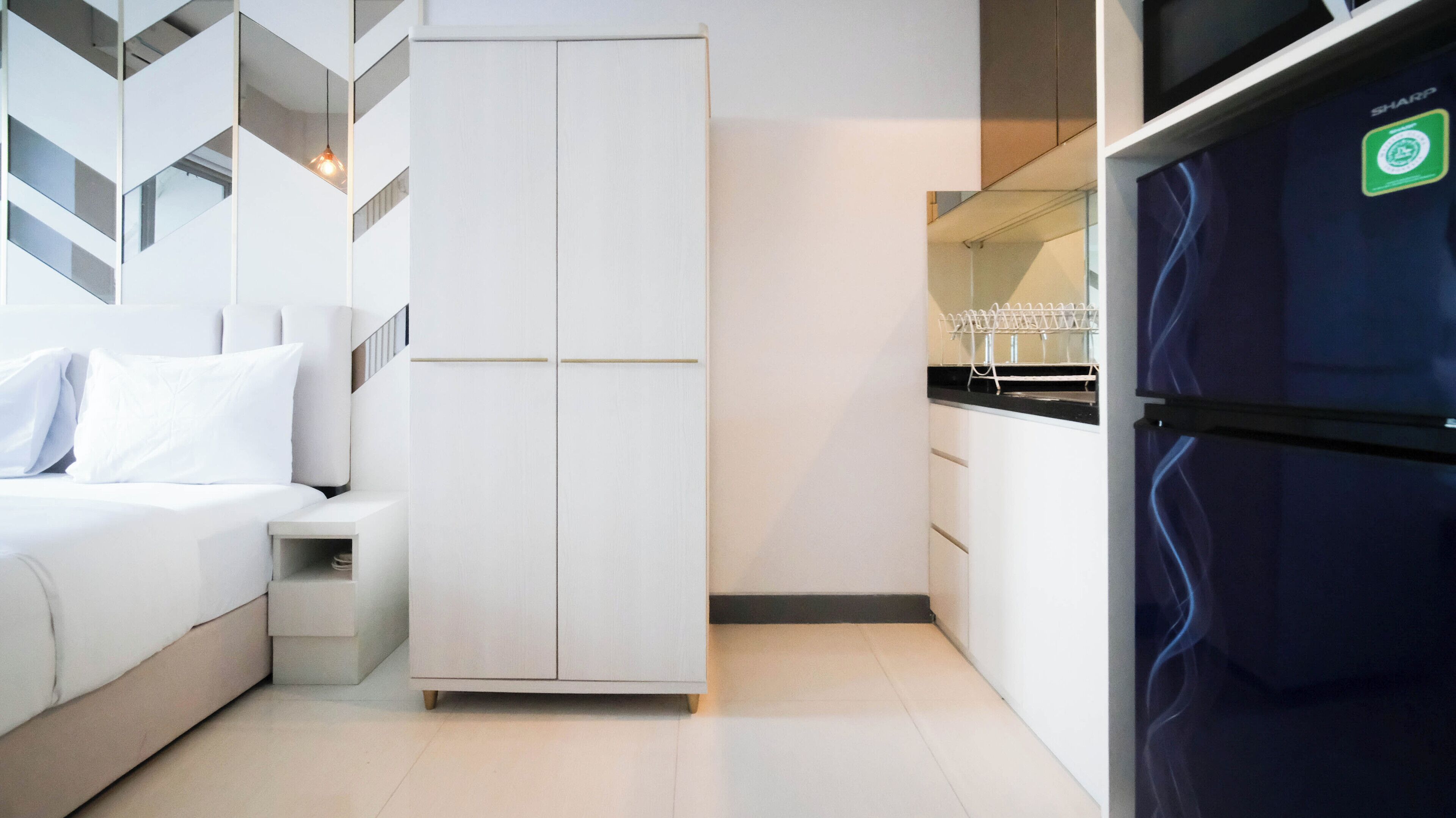 A modern bedroom with a bed, a wardrobe, and a built-in kitchen area.