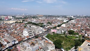 A densely packed urban area with a mix of residential and commercial buildings, including a prominent white building with a green roof and a pink building. - Tranquil Designed 2Br At Gateway Ahmad Yani Cicadas Apartment (Bandung)
