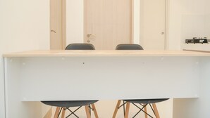 A conference table with two chairs, a wooden door, and a white wall with a shelf. - Fancy And Nice 2Br Apartment At Tokyo Riverside Pik 2 (Teluknaga)