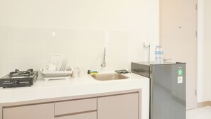 A kitchen with a gas stove, sink, and a refrigerator. - Fancy And Nice 2Br Apartment At Tokyo Riverside Pik 2 (Teluknaga)