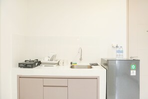 A compact kitchen with a gas stove, sink, and a refrigerator. - Fancy And Nice 2Br Apartment At Tokyo Riverside Pik 2 (Teluknaga)