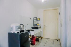 Uma cozinha compacta equipada com geladeira, cafeteira, chaleira, pia e fogão a gás.