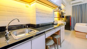 A modern kitchen with a black countertop, stainless steel sink, and white cabinets. - Cozy Stay And New Furnished Studio At Transpark Cibubur Apartment (Depok)