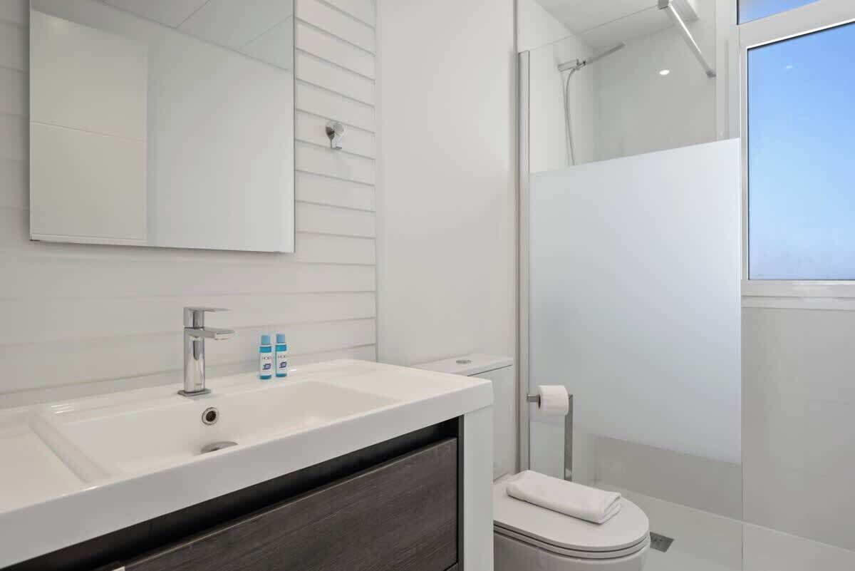 A modern bathroom with a white sink, mirror, and toilet.