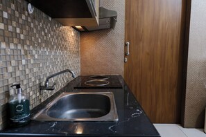 A modern kitchen with a black countertop, stainless steel sink, and a tiled backsplash.