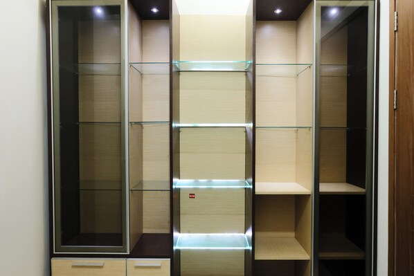 A walk-in closet with multiple shelves and drawers, featuring a combination of open and closed storage options.