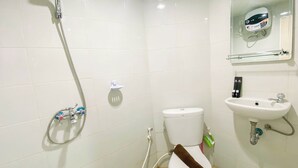 Een badkamer met douche, toilet, wastafel en spiegel met een digitaal apparaat.