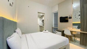 Een moderne hotelkamer met een net opgemaakt bed, een bureau met stoel, een flatscreen televisie en een spiegel.