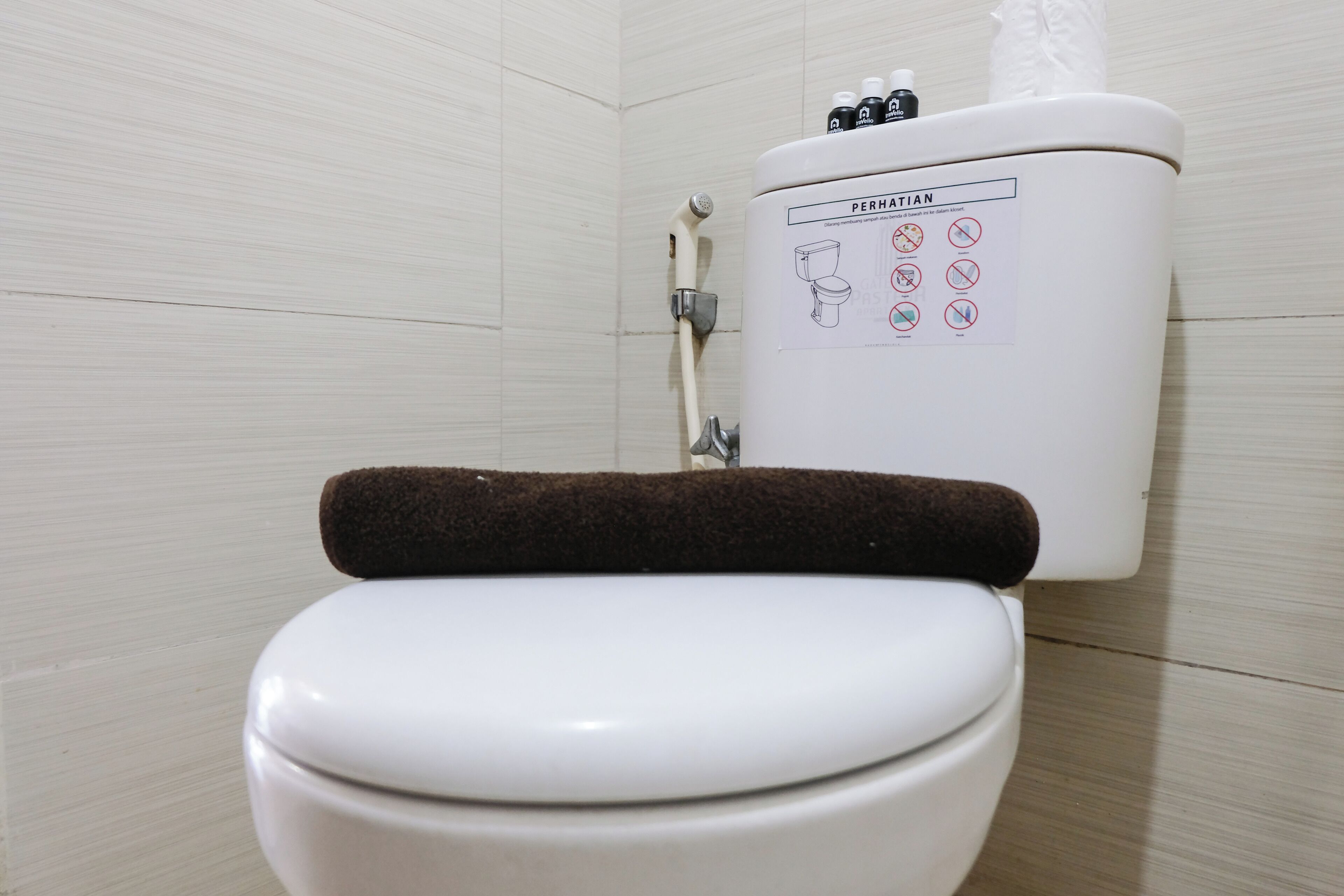 A toilet with a brown seat cover and a water tank with instructions.