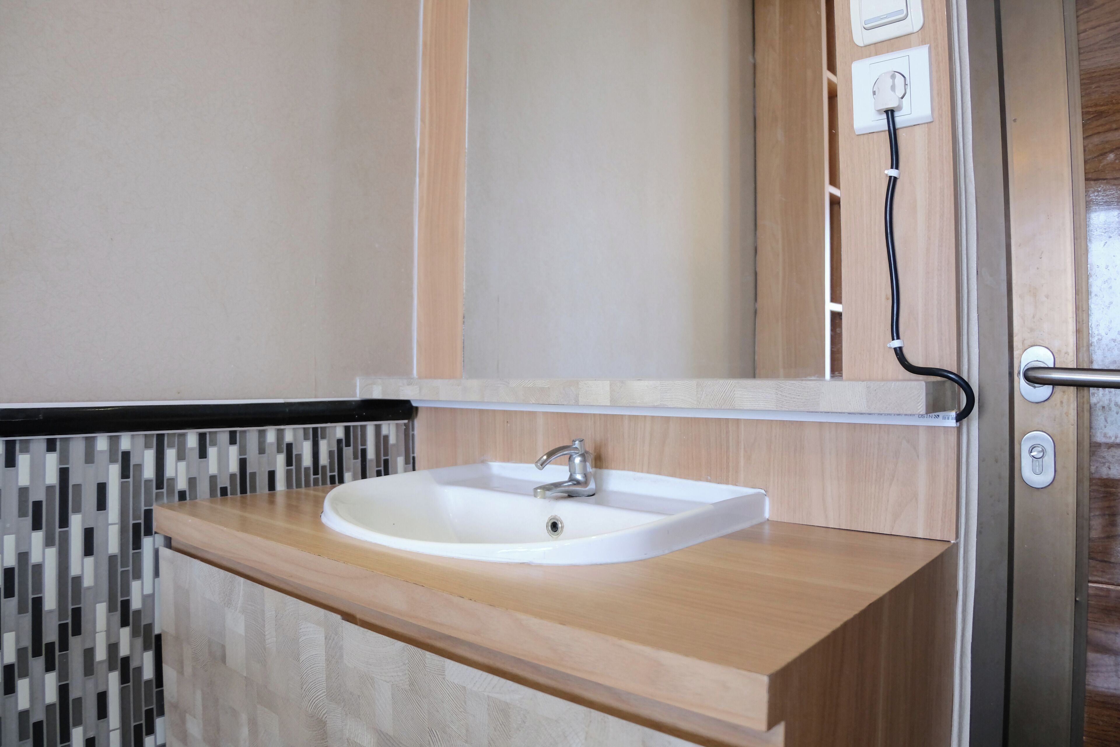 A bathroom with a white sink, a mirror, and a tiled backsplash.