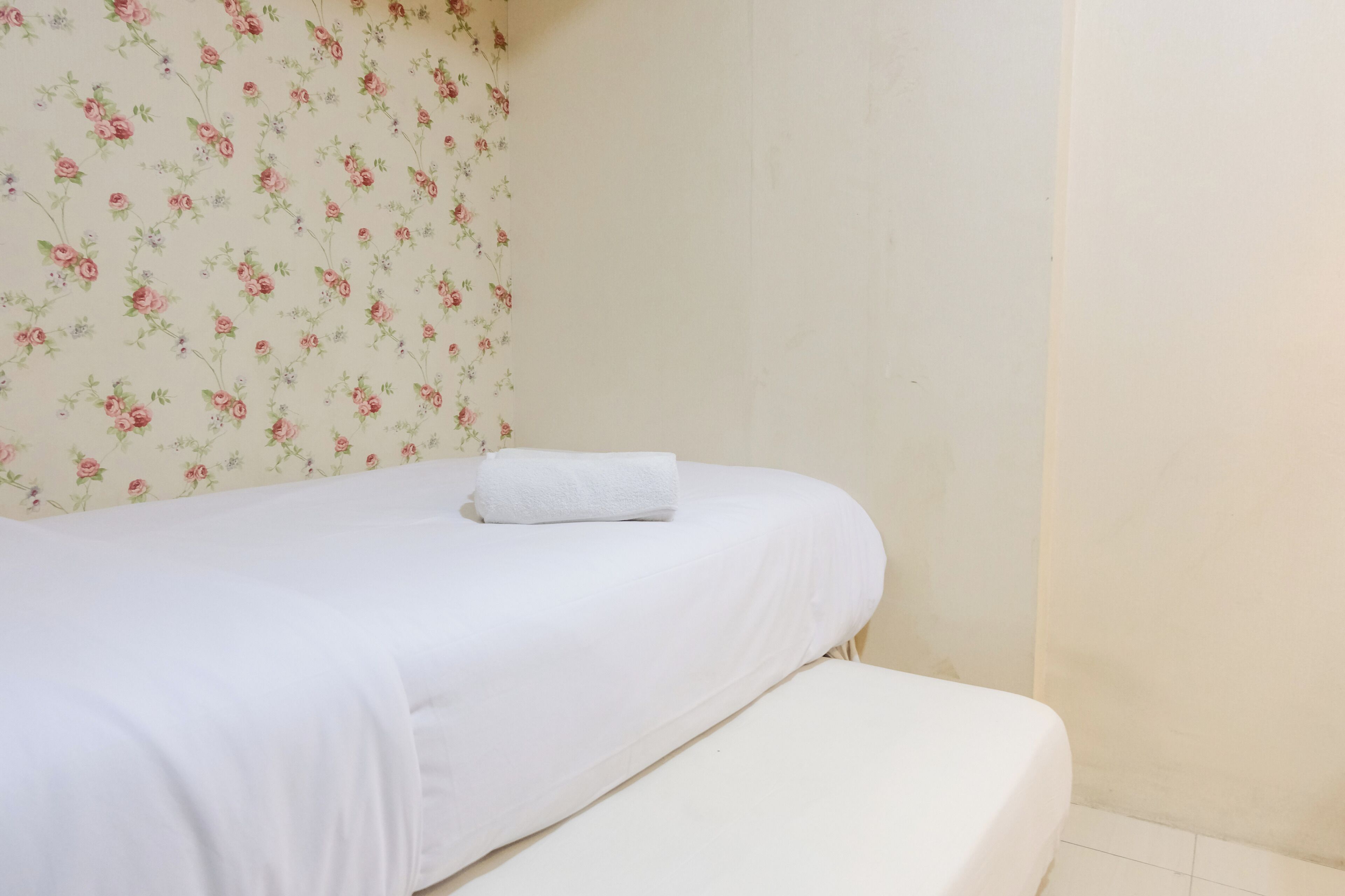 A single bed with a white sheet and a neatly folded white towel.